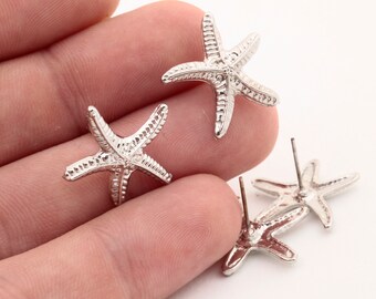 May include: A pair of silver starfish earrings. The earrings are made of metal and have a textured surface. The starfish are about 1 inch in diameter.