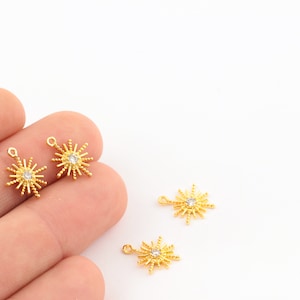 May include: Four gold-toned starburst charms with a clear rhinestone center. Each charm has a loop for attaching to jewelry.