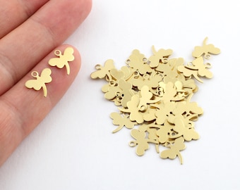 May include: A pile of gold-colored metal dragonfly charms with a small loop at the top. The charms are about 1 inch in size.