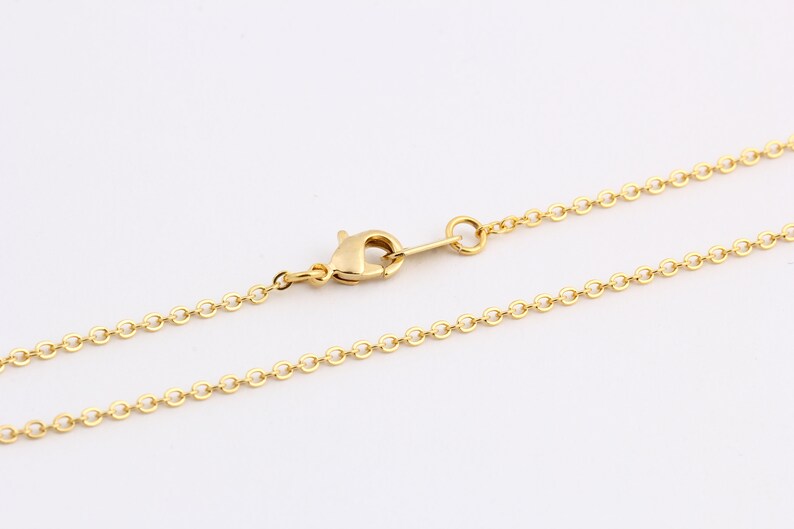 K&ouml;nnte beinhalten: Eine goldene Kettenkette mit einem Karabinerverschluss.
