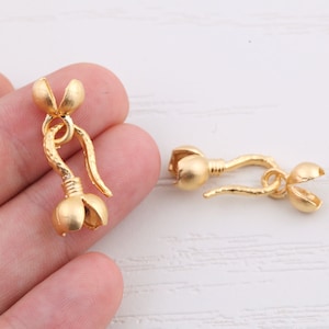 May include: Two gold-toned metal clasps for jewelry making. One clasp is a hook and loop design, the other is a flower-shaped design.