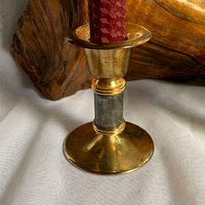 Op de afbeelding: Een gouden kandelaar met een marmeren voet. De kandelaar heeft een ronde bovenkant en een brede voet. De marmeren voet is donkergrijs met witte aderen.