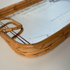 May include: A rectangular bamboo serving tray with a mirrored surface. The tray has a handle on one side and features the text "Johnnie Walker Old Scotch Whisky". The tray is a light brown color.