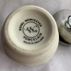 K&ouml;nnte beinhalten: Nahaufnahme einer wei&szlig;en Keramikdose mit einem schwarz-wei&szlig;en Etikett mit der Aufschrift "Royal Worcester Porcelain Made in England".