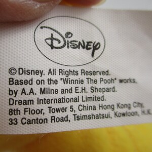 May include: White tag with black text stating "Disney. All Rights Reserved. Based on the "Winnie The Pooh" works, by A.A. Milne and E.H. Shepard. Dream International Limited. 8th Floor, Tower 5, China Hong Kong City, 33 Canton Road, Tsimshatsui, Kowloon, H.K."