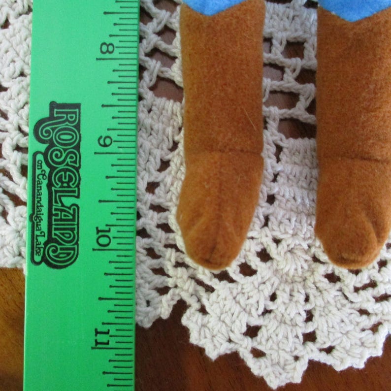 Puede incluir: Primer plano de dos botas de vaquero de fieltro marr&oacute;n con la parte superior de fieltro azul. Las botas descansan sobre un tapete de ganchillo color crema. Una regla verde con el texto "Roseland on Canandaigua Lake" est&aacute; a la izquierda.