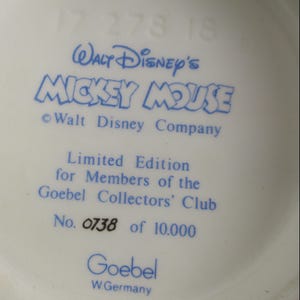 May include: A close-up of a white ceramic surface with blue text. The text reads "Walt Disney's Mickey Mouse" and "Limited Edition for Members of the Goebel Collectors' Club". The number "0738 of 10.000" is also visible.