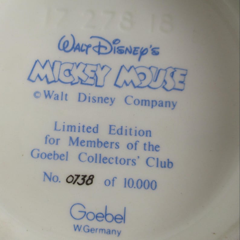 May include: A close-up of a white ceramic surface with blue text. The text reads "Walt Disney's Mickey Mouse" and "Limited Edition for Members of the Goebel Collectors' Club". The number "0738 of 10.000" is also visible.
