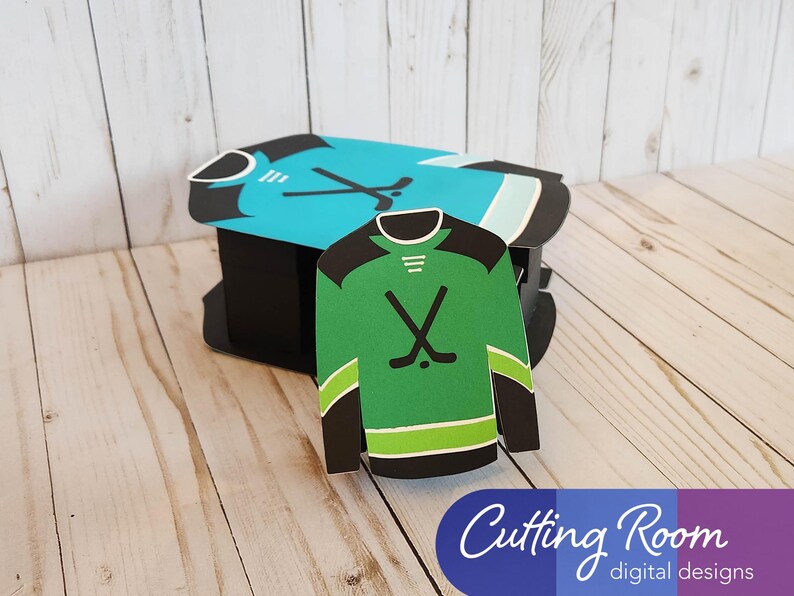 The large hockey gift box is sitting on a wood surface with the smaller gift card sized hockey jersey box propped up against it.