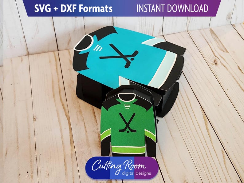 A digital download of an SVG and DXF file for a hockey jersey box. The larger box is blue and the smaller one is green. The text 'SVG + DXF DIGITAL DOWNLOAD' is at the top of the image. The text 'Cutting Room digital designs' is at the bottom of the image.