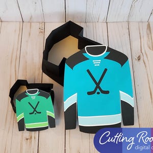 Two hockey jersey shaped boxes, one is green and the other is blue. Both boxes have a hockey stick design and are open to reveal the inside. The text 'Cutting Room digital designs' is at the bottom of the image.