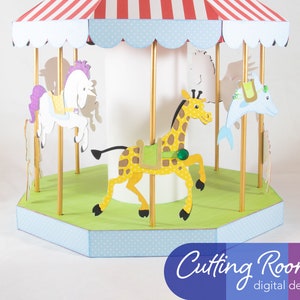 A papercraft carousel with a red and white striped roof, a blue and white polka dot base, and a white center pole. The carousel has four animals: a white horse with a purple mane, a yellow giraffe, a blue dolphin, and a white horse with a brown mane. The carousel is on a white background. Cutting Room digital designs.