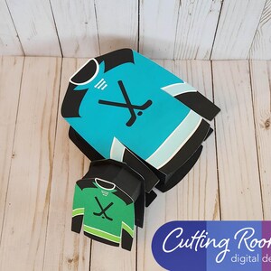 May include: Two hockey jersey shaped boxes, one blue and one green, with a hockey stick and puck graphic. The boxes are layered on top of each other. The text "Cutting Room digital designs" is visible in the bottom right corner.