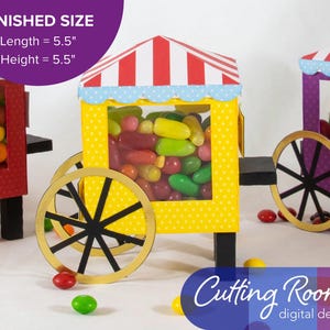 Three papercraft candy carts with red, yellow, and purple bodies. Each cart has a striped red and white roof with a scalloped blue trim. The carts are filled with colorful jelly beans and have black wheels with gold rims. The text 'Cutting Room digital designs' is in blue on a purple background.  There is a banner indicating that they are each about 5.5 inches long and 5.5 inches tall.