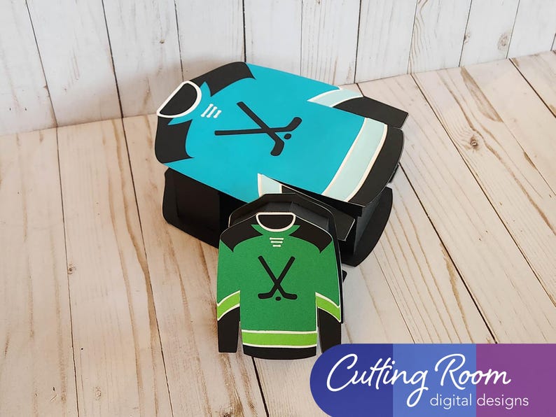 A hockey jersey shaped box with a blue and white jersey design and a smaller gift card or treat box size hockey jersey box is next to it.