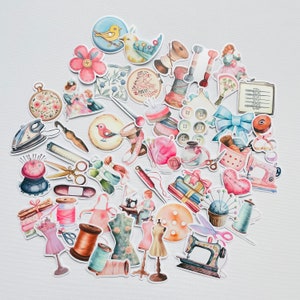 Könnte beinhalten: Eine Sammlung bunter Aquarell-Aufkleber mit Näh- und Bastelmotiven. Die Aufkleber zeigen Bilder von Nähmaschinen, Garnrollen, Knöpfen, Nadeln, Scheren und anderen Nähutensilien. Es gibt auch einige niedliche Tier- und Blumenmotive.