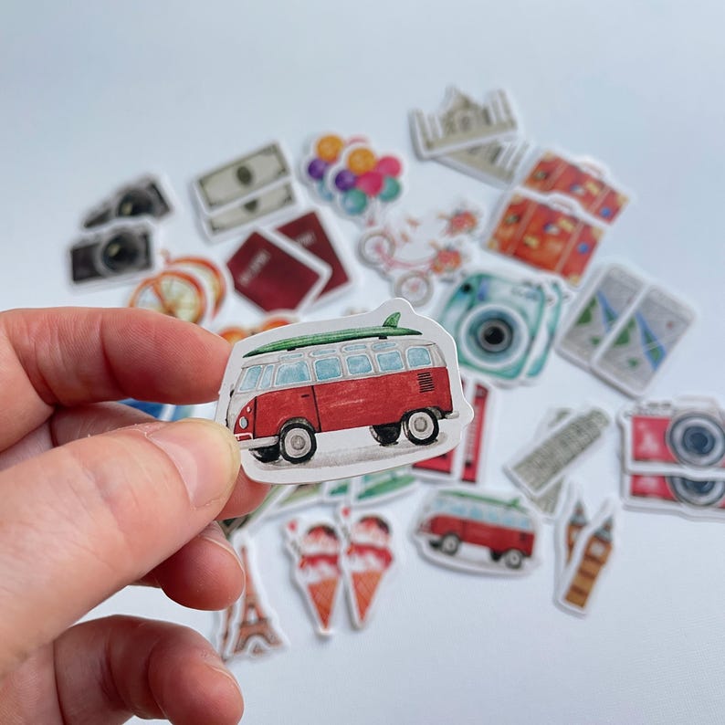 Op de afbeelding: Een verzameling stickers met reisthema, waaronder een rood-witte camper met een groen surfboard op het dak, een camera, een paspoort, valuta, ballonnen, ijshoorntjes en diverse bezienswaardigheden, allemaal in een aquarel illustratiestijl.