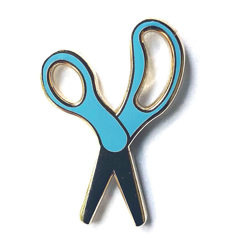 Op de afbeelding: Een gouden metalen pin in de vorm van een schaar met blauwe handvatten.