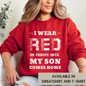 May include: A red sweatshirt with white text that reads "I WEAR RED on Fridays until MY SON COMES HOME." The text is arranged vertically and horizontally. The bottom of the image says "AVAILABLE IN SWEATSHIRT AND T-SHIRT."