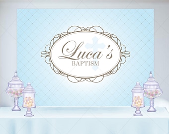 May include: A light blue backdrop with a diamond pattern and the text "Luca's Baptism" in a decorative frame. A white tablecloth is in front of the backdrop, with three glass jars filled with colorful candies.