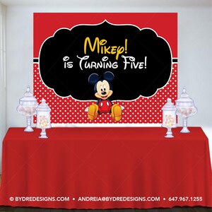 K&ouml;nnte beinhalten: Eine rote Tischdecke mit einem Hintergrund mit Micky Maus und dem Text "Mikey! is Turning Five!". Der Hintergrund hat eine schwarze Form mit gelbem Text, ein rot-wei&szlig;es Tupfenmuster und einen roten oberen Rand. Glasbeh&auml;lter mit S&uuml;&szlig;igkeiten stehen auf dem Tisch.