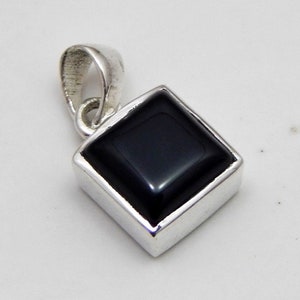 May include: A square black onyx pendant with a silver-colored bail. The onyx is set in a square silver frame. The pendant is a simple, elegant design.