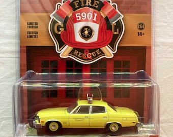 May include: A yellow 1977 AMC Matador diecast model car with a red light on top. The car is labeled "Dallas, Texas Fire Department" and is part of a Greenlight Collectibles series. The packaging features a red fire helmet with the number 5901 and the words "Fire Rescue".
