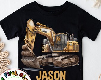 Puede incluir: Camiseta negra con un gráfico de excavadora amarilla y el nombre "JASON" impreso en letras doradas. La camiseta tiene mangas cortas y cuello redondo.