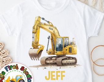 Puede incluir: Camiseta blanca con un diseño de excavadora amarilla y el nombre "JEFF". La excavadora tiene un estilo acuarela detallado. La camiseta también tiene un logotipo de "Kids First Studio".