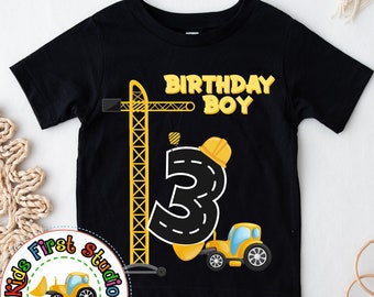 Puede incluir: Camiseta negra con un camión de construcción amarillo y el número 3. El texto "Birthday Boy" está por encima del número.