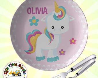 May include: Pink children's plate with a white unicorn with a rainbow mane and tail. The plate has a white star pattern and the name "OLIVIA" is printed on the plate.