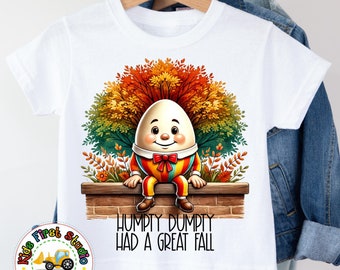 May include: White t-shirt with a cartoon illustration of Humpty Dumpty sitting on a brick wall. The illustration features a fall foliage background and the text "Humpty Dumpty Had A Great Fall".