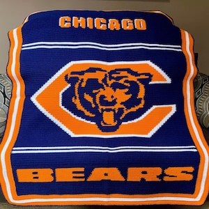 May include: A navy blue crocheted blanket with an orange and white Chicago Bears logo. The logo features a bear's head inside a "C" with the word "CHICAGO" above and "BEARS" below.