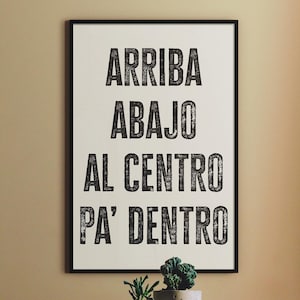 以下が含まれることがあります： 「ARRIBA, ABAJO, AL CENTRO, PA' DENTRO」という黒い太字の言葉が書かれた額入りのプリント。2つの小さな鉢植えが、木製のテーブルのフレームの下に置かれています。フレームは黒色です。
