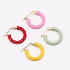 Può includere: Quattro paia di orecchini a cerchio in diversi colori: rosa, rosso, verde e giallo. Gli orecchini sono in metallo dorato e hanno un design semplice e minimalista.