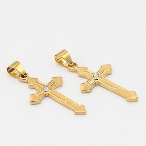 Peut inclure: Deux pendentifs en forme de croix dorés, chacun avec un seul strass transparent au centre.