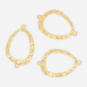 May include: Three gold-toned metal oval-shaped pendant blanks with a textured surface. Each blank has two jump rings attached.