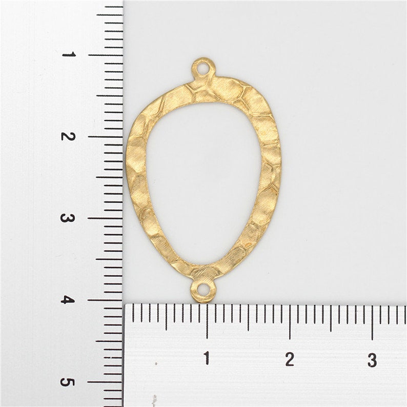 May include: Gold-toned metal pendant with a hammered texture and an oval shape. The pendant measures approximately 2 inches in height.