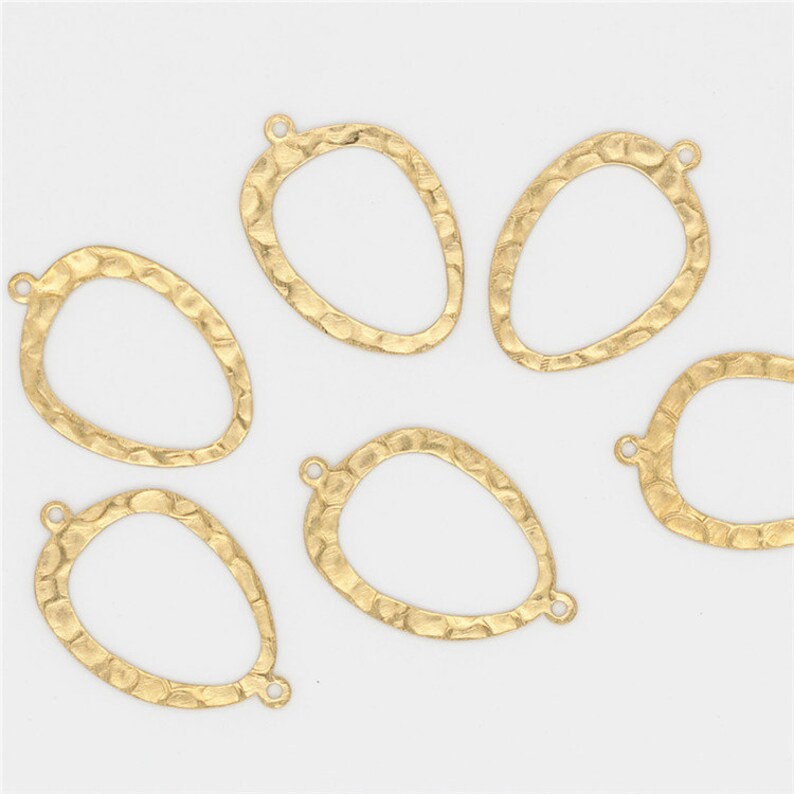 May include: Six gold-toned metal oval-shaped pendant charms with a hammered texture. Each charm has a loop at the top for attaching to jewelry.
