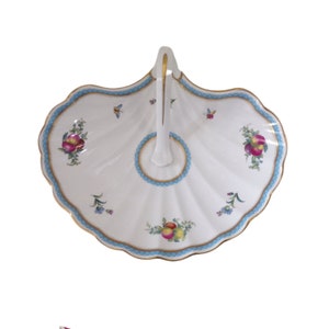 May include: A white porcelain serving dish with a scalloped edge and a blue and gold trim. The dish has a handle and features a floral design with fruit.