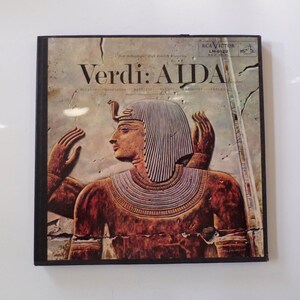 May include: Vintage vinyl record album cover for Verdi's Aida. The cover features a detailed relief sculpture of an Egyptian pharaoh with a headdress and ornate collar. The album title is in large, bold letters.