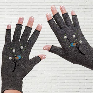 May include: A pair of gray fingerless gloves with a floral design and a small bird on each glove. The gloves are made of a soft, breathable material and are designed to provide comfort and support.