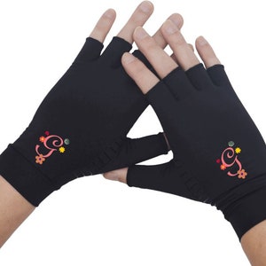 May include: A pair of black fingerless gloves with a pink embroidered letter "G" and colorful flowers on each glove.
