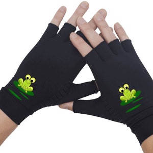 K&ouml;nnte beinhalten: Schwarze fingerlose Handschuhe mit einem gr&uuml;nen Frosch-Design auf jedem Handschuh. Der Frosch sitzt auf einem Seerosenblatt.