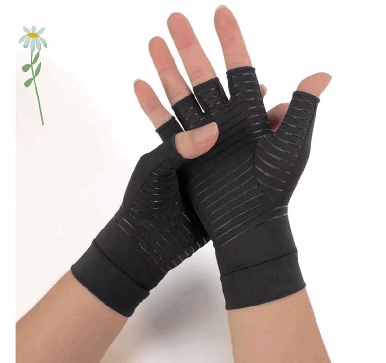 K&ouml;nnte beinhalten: Ein Paar schwarze fingerlose Kompressionshandschuhe mit einem strukturierten Design. Die Handschuhe werden an den H&auml;nden einer Person getragen.