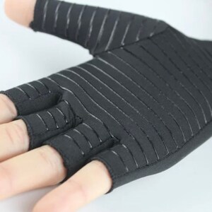 K&ouml;nnte beinhalten: Schwarze fingerlose Handschuhe mit einem gestreiften Muster. Die Handschuhe haben ein fingerloses Design mit offenen Fingerspitzen.