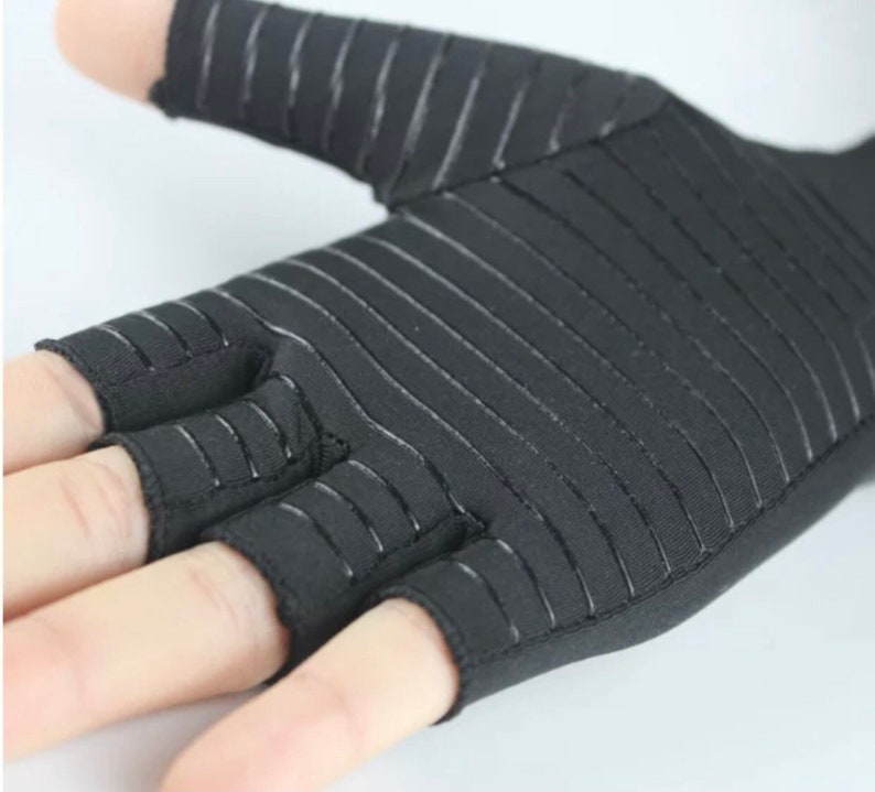 K&ouml;nnte beinhalten: Schwarze fingerlose Handschuhe mit einem gestreiften Muster. Die Handschuhe haben ein fingerloses Design mit offenen Fingerspitzen.