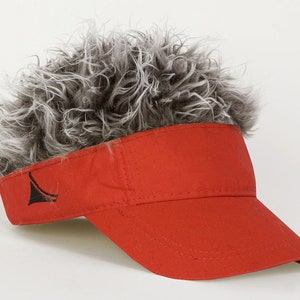 May include: A red visor with a gray and white faux fur mohawk attached to the top.