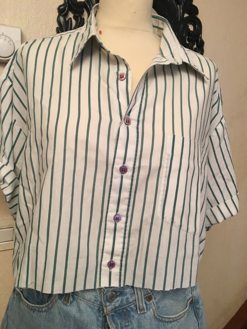 Peut inclure: Une chemise &agrave; manches courtes boutonn&eacute;e &agrave; rayures blanches et vertes avec une poche sur le c&ocirc;t&eacute; gauche. La chemise a une ourlet court et est faite d'un tissu l&eacute;ger.