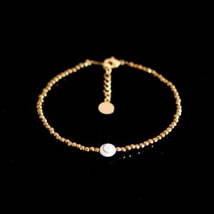 Peut inclure: Un bracelet en perles dorées avec un charme en coquille blanche. Le bracelet a une fermeture à fermoir.